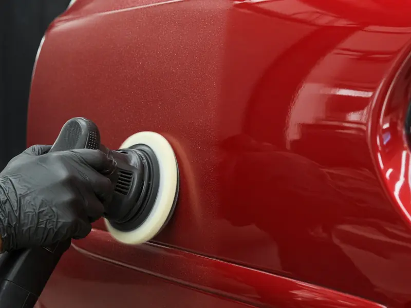 Polisher correcting paint on a red car (illustrative image)